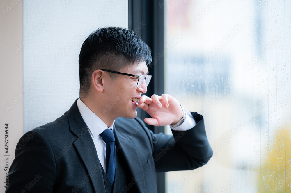 성공한 느낌으로 보이는 빌딩에서 밖을 바라보며 웃는 정장의 사업가 복사 공간 있음 성공한 느낌으로 보이는 빌딩에서 밖을 바라보며 웃는 정장의 사업가 복사 공간 있음