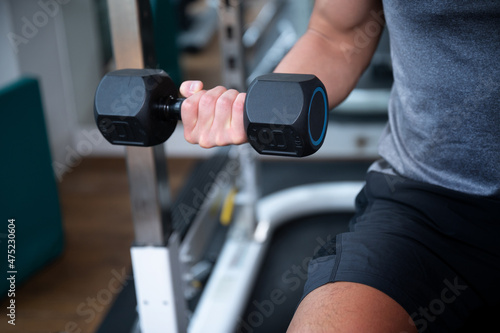 Close-up of an Asian man's hand while training with dumbbells. © kapinon