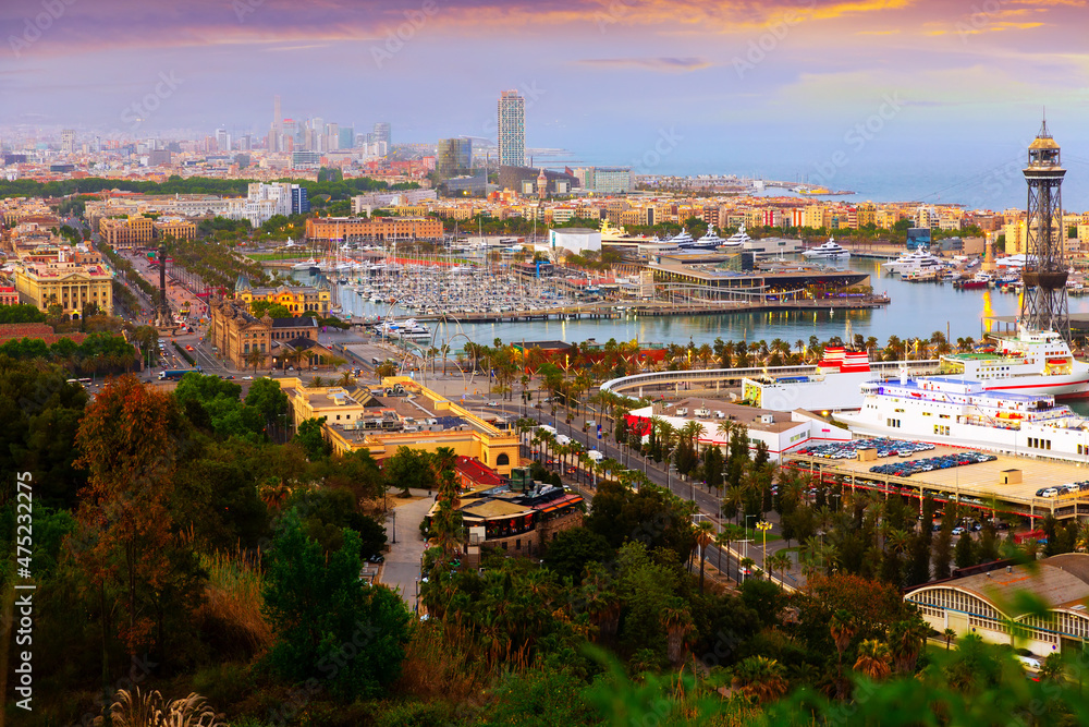 Aerial panoramic view of modern Barcelona cityscape on Mediterranean coast with seaport on spring evening, Spain.