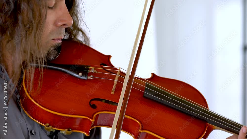 Close up profile of hispanic male musician with long hair and goatee playing red viola Close up profile of hispanic male musician with long hair and goatee playing red viola