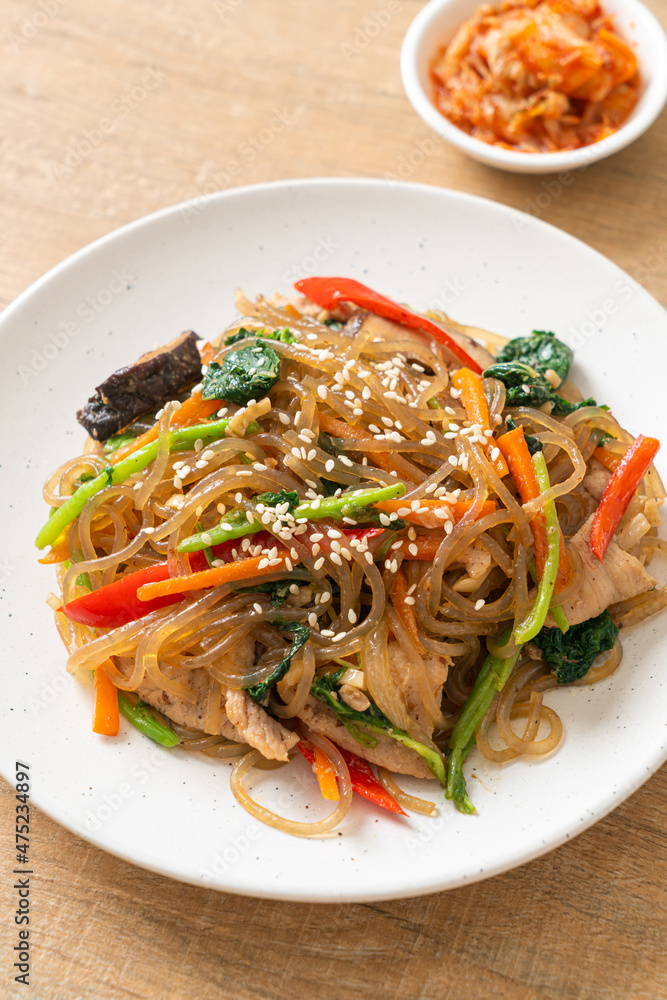 japchae or stir-fried Korean vermicelli noodles with vegetables and pork topped with white sesame