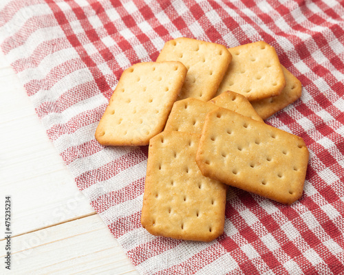Cracker cookies with tablecloth on white wooden table background.