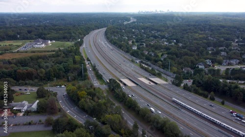 A 4k aerial video with an upward pan of a Silver Line Metro Train traveling down the Dulles Access Road with Tysons Corner in the distance.