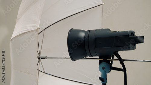 Big studio flashlight on a tripod and softbox paper in large size studio for video or film production. © gnepphoto