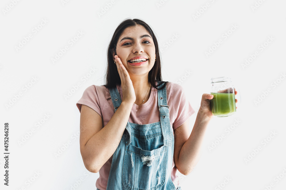 Happy young latin woman holding bottle of green juice on white background in Latin America Happy young latin woman holding bottle of green juice on white background in Latin America