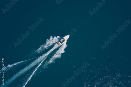 White speed boat fast movement on the water top view. Diagonal boat movement on blue water top view. Travel - image. Top view of a white high-speed boat. © Berg