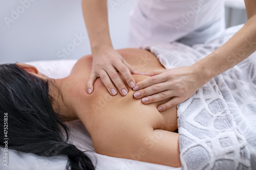 Back massage close-up. Skin care. The hands of the masseur knead the skin of a young woman. Horizontal photo.