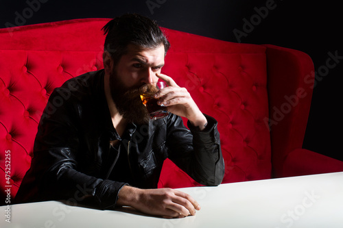 Bearded man drinking whisky, whiskey or cognac brandy. Hipster brutal man drinker alcoholic with alcoholism problem, alcohol abuse addiction concept. Drunken man behavior.