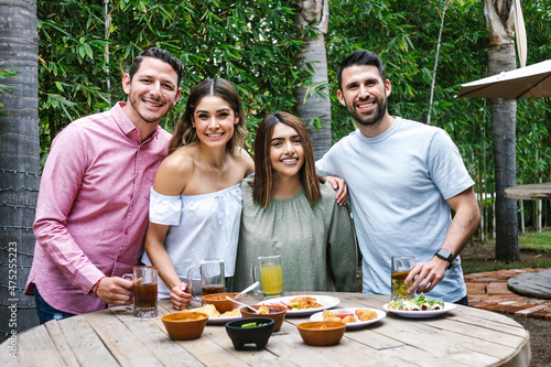 Group of young latin friends meeting for beer, michelada drinks and mexican food making a toast in restaurant terrace in Mexico Latin America