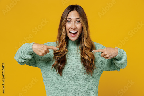 Fotografija Young amazed surprised exultant fun caucasian woman 30s wearing green knitted sweater point index finger on herself isolated on plain yellow color background studio portrait