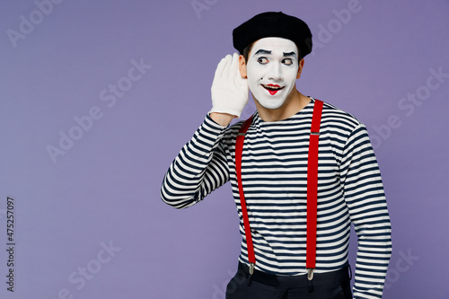 Curious nosy charismatic fun young mime man with white face mask wears striped shirt beret try to hear you overhear listening intently isolated on plain pastel light violet background studio portrait. photo