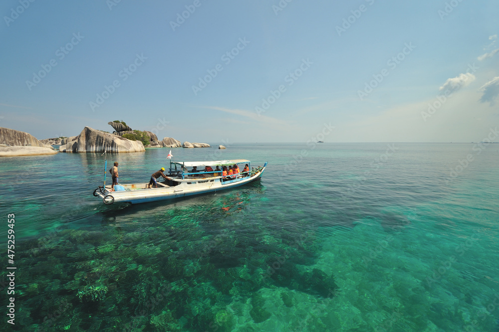 Tourist boat with full of passengers cruising near Pulau Burung (Bird shaped stone island) in Belitung, Indonesia. 