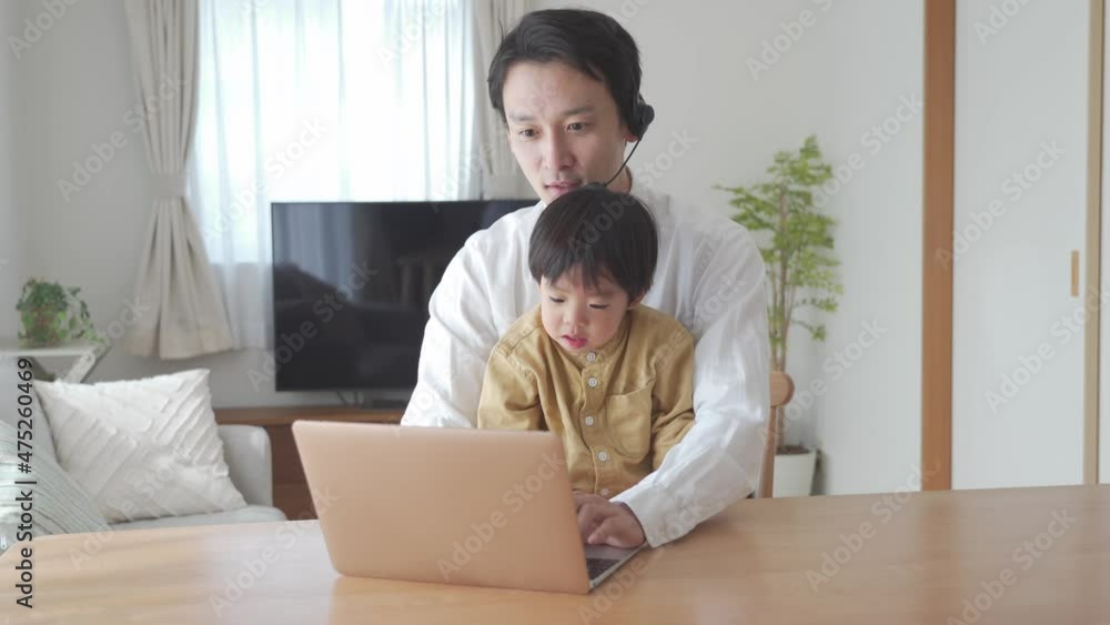 家でパソコン作業をする父親と息子 家でパソコン作業をする父親と息子