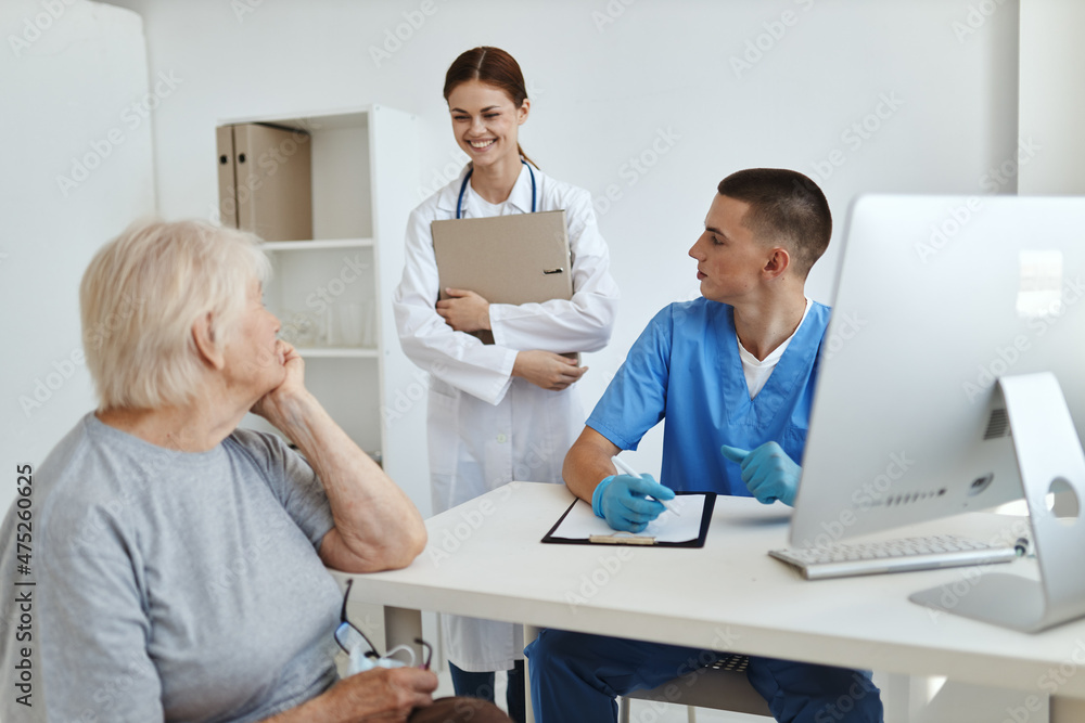 Fototapeta premium female patient sitting in hospital office with doctor and nurse communicating
