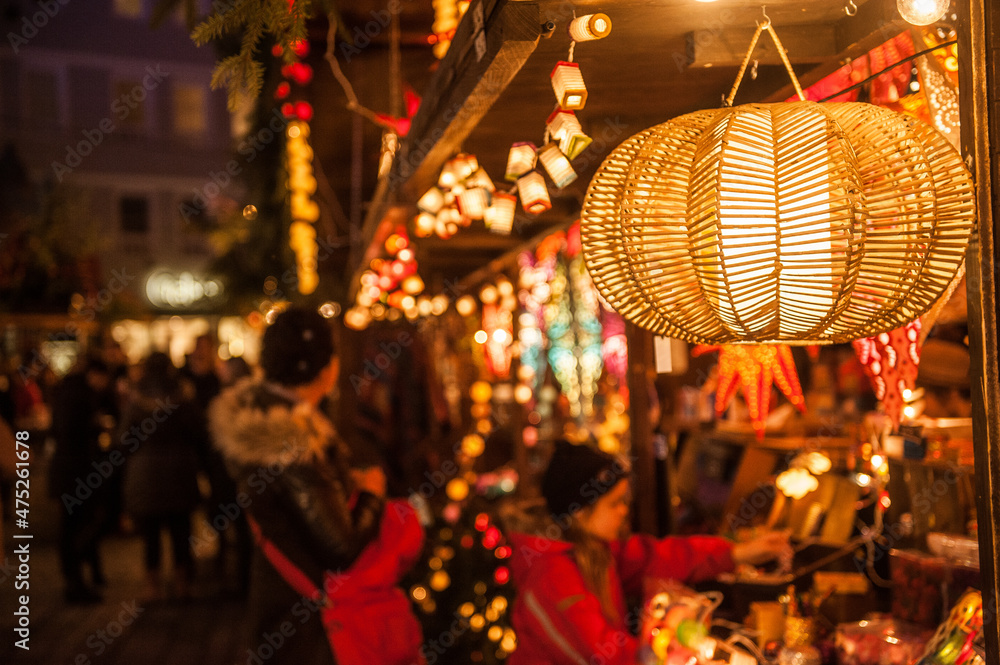 Lampe mit Bastgeflecht an weihnachtlichem Marktstand vor unscharfem Hintergrund