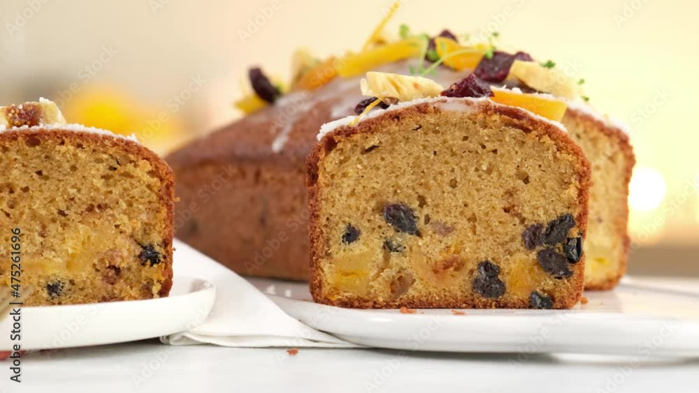 Close-up. A sliced fruitcake soaked in rum is on the table. Christmas atmosphere with lanterns in the background. Christmas homemade muffin. Traditional cupcake with dried fruits. Camera movement. Close-up. A sliced fruitcake soaked in rum is on the table. Christmas atmosphere with lanterns in the background. Christmas homemade muffin. Traditional cupcake with dried fruits. Camera movement.