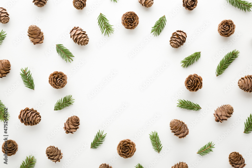 Round frame created from dry brown cones and green fir branches on white table background. Christmas natural decoration pattern. Empty place for inspirational wishes text, quote or sayings. Top view. Round frame created from dry brown cones and green fir branches on white table background. Christmas natural decoration pattern. Empty place for inspirational wishes text, quote or sayings. Top view.