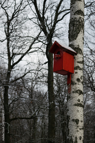 Bright red snowy birdhouse on a tree