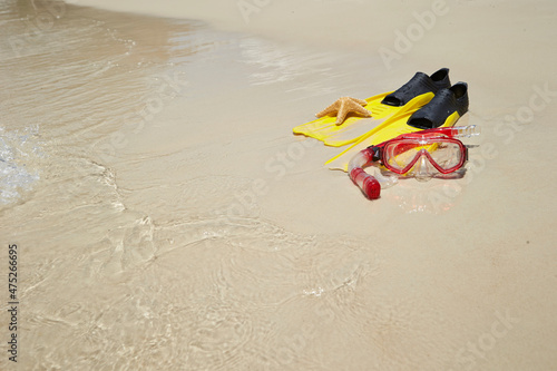 Yellow flippers, snorkel set and starfish on the beach