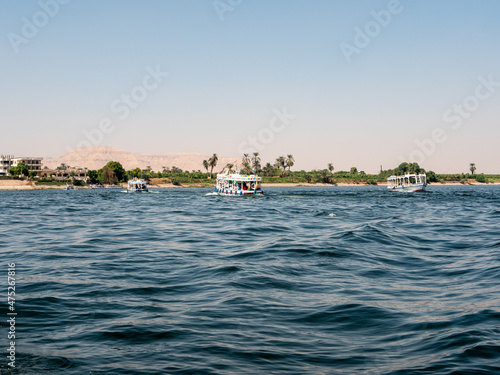 Luxor, Egypt - October 3, 2021: View of the Nile river and the coastline of Luxor. Boats transport people from one bank to the opposite bank along the Nile river.