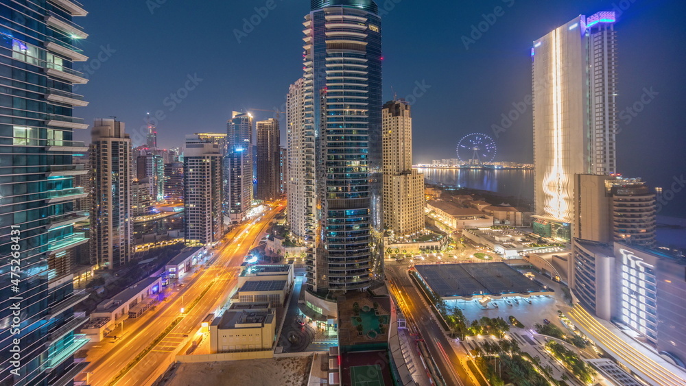 Obraz premium Panoramic view of the Dubai Marina and JBR area and the famous Ferris Wheel aerial night to day timelapse