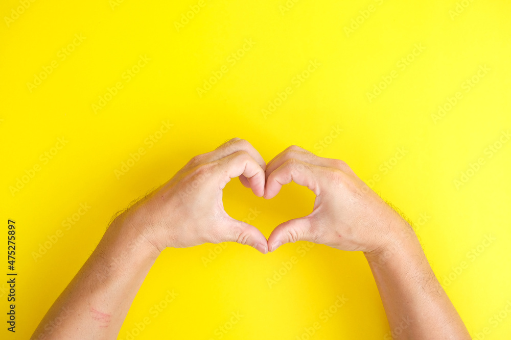 Obraz premium Hands in the shape of a heart on a yellow background
