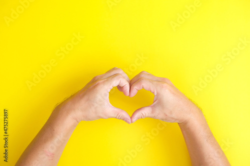 Hands in the shape of a heart on a yellow background