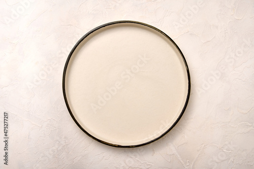 Empty white ceramic plate with black rim on a light textured background, flat lay, copy space