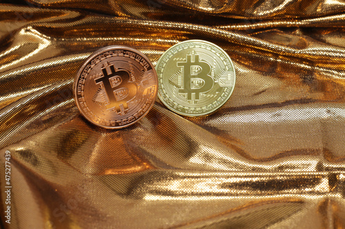 A copper and gold colored physical bitcoin before golden texture background that looks like molten gold, narrow focus on right gold colored coin