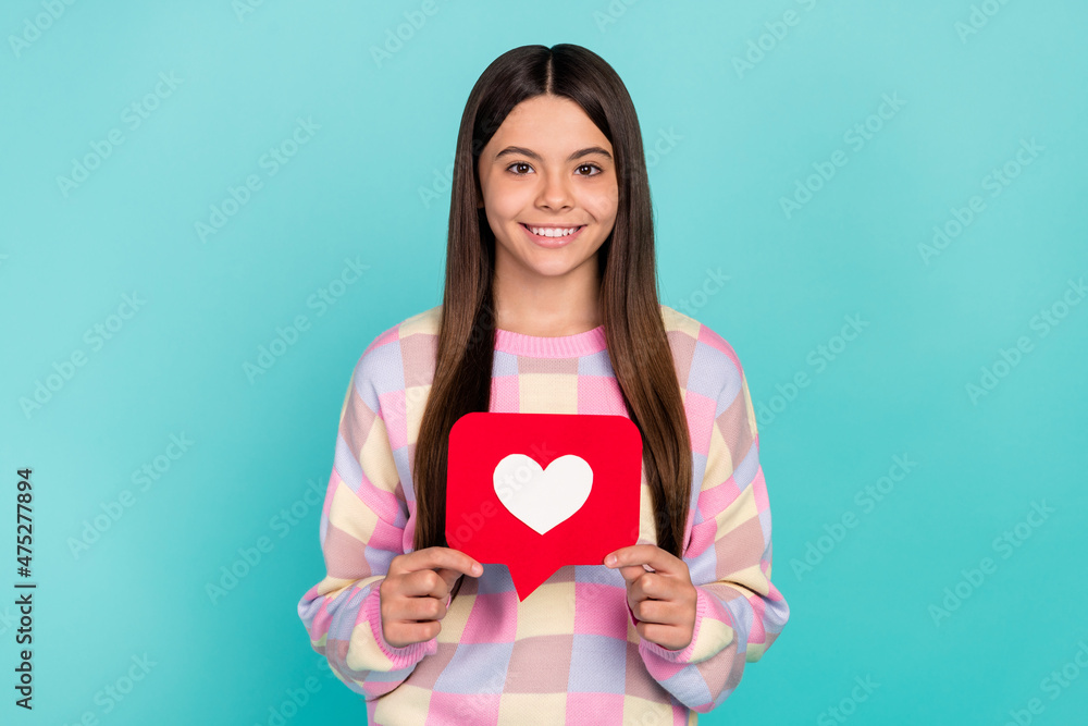 Photo of sweet charming school girl dressed prink pullover holding heart like sign isolated teal color background Photo of sweet charming school girl dressed prink pullover holding heart like sign isolated teal color background
