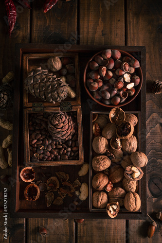 a wooden tray full of different types of nuts. whole and chopped nuts in different boxes piled next