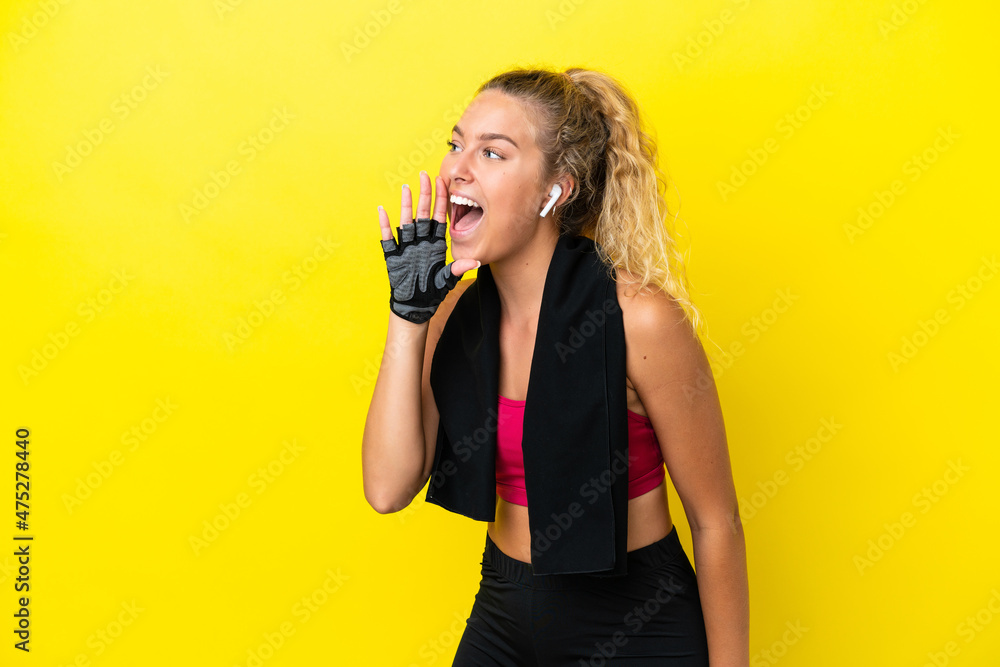 Sport woman with towel isolated on yellow background shouting with mouth wide open to the lateral Sport woman with towel isolated on yellow background shouting with mouth wide open to the lateral