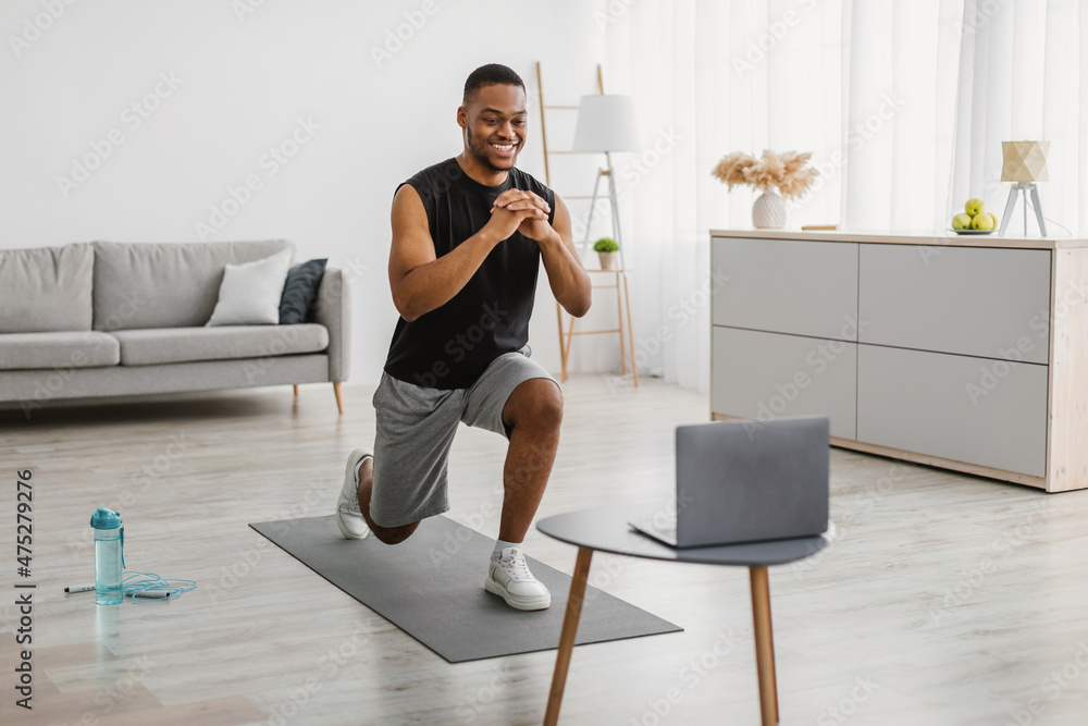 African Man Doing Forward Lunge Exercise Watching Online Workout Indoor African Man Doing Forward Lunge Exercise Watching Online Workout Indoor