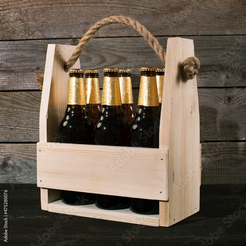 Beer bottles in a wooden beer crate on wooden background. Rustic, rural style.