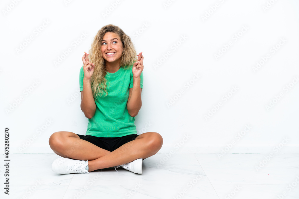 Girl with curly hair sitting on the floor with fingers crossing Girl with curly hair sitting on the floor with fingers crossing