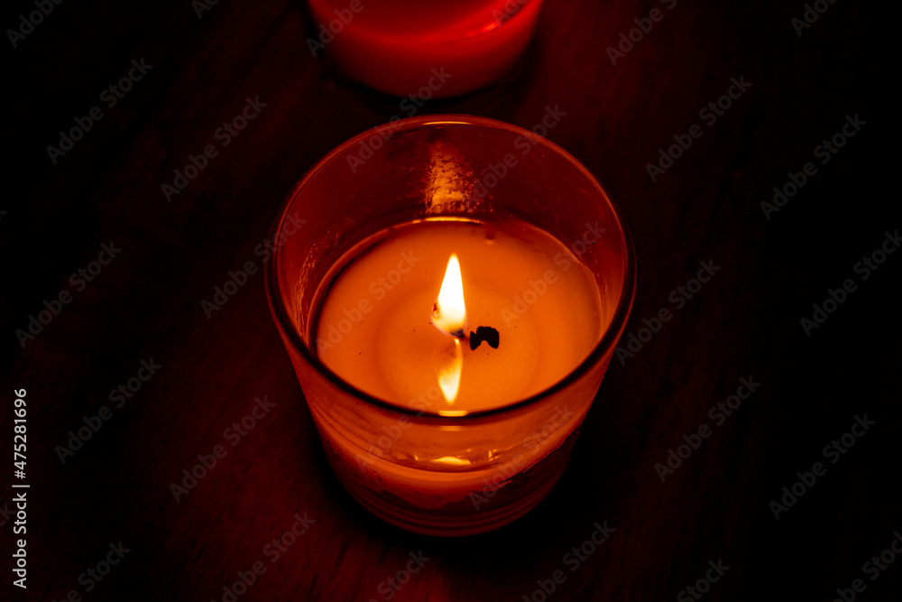 Red candle burning in dark with focus on single candle in foreground. Red candle burning in dark with focus on single candle in foreground.