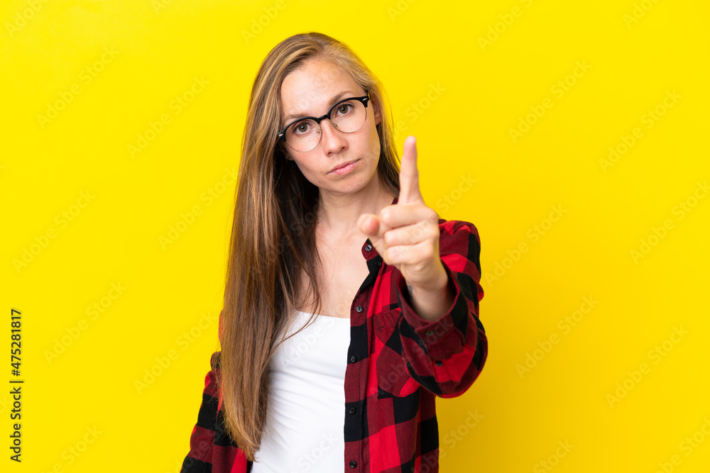 Young English woman isolated on yellow background frustrated and pointing to the front Young English woman isolated on yellow background frustrated and pointing to the front