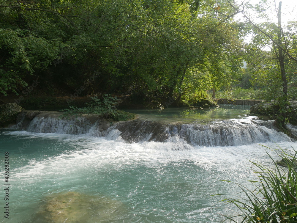 Obraz premium waterfalls along the bed of the Elsa river carved into the rock among the vegetation in Sentierelsa river Park