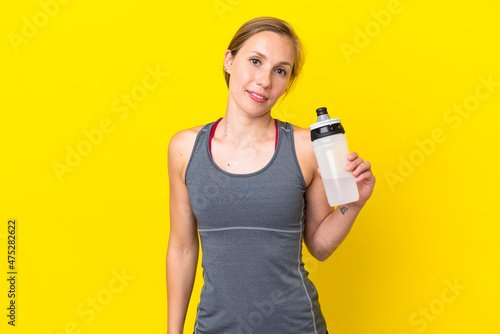 Young English woman isolated on yellow background with sports water bottle