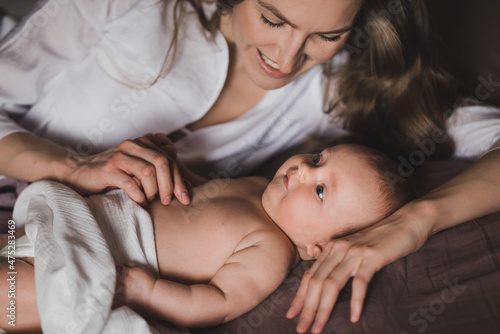 Beautiful young mother holds newborn baby girl in white lighter room at home. Tenderness cozy atmosphere