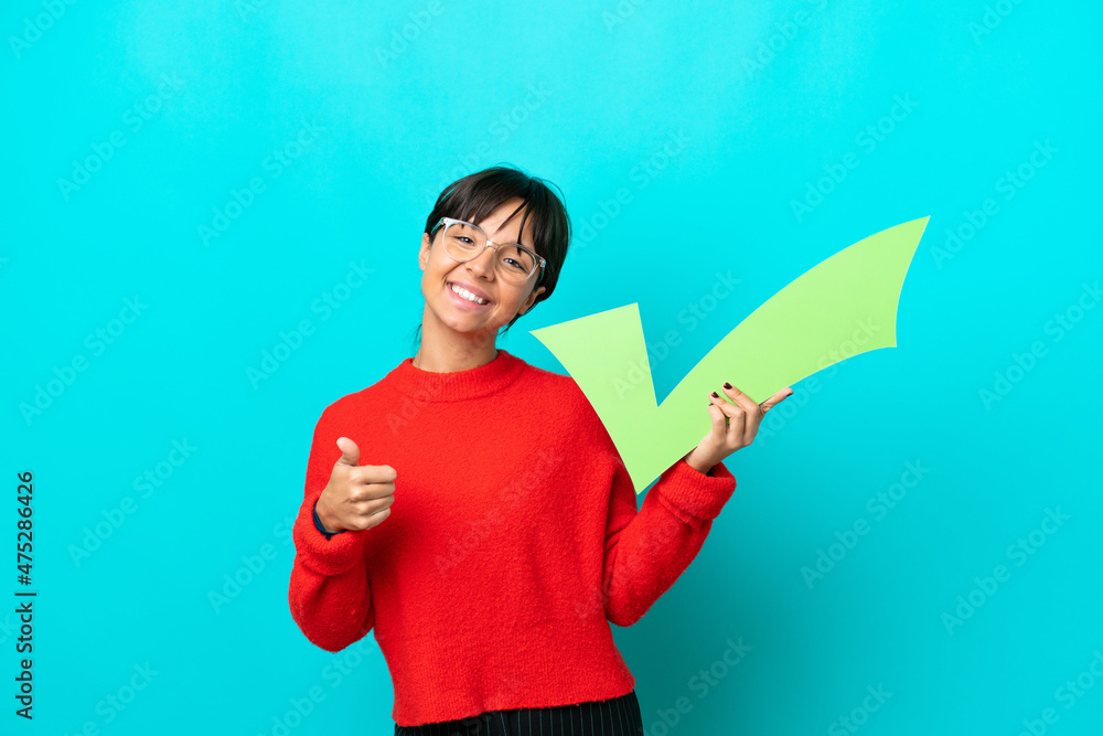 Young woman isolated on blue background holding a check icon with thumb up Young woman isolated on blue background holding a check icon with thumb up