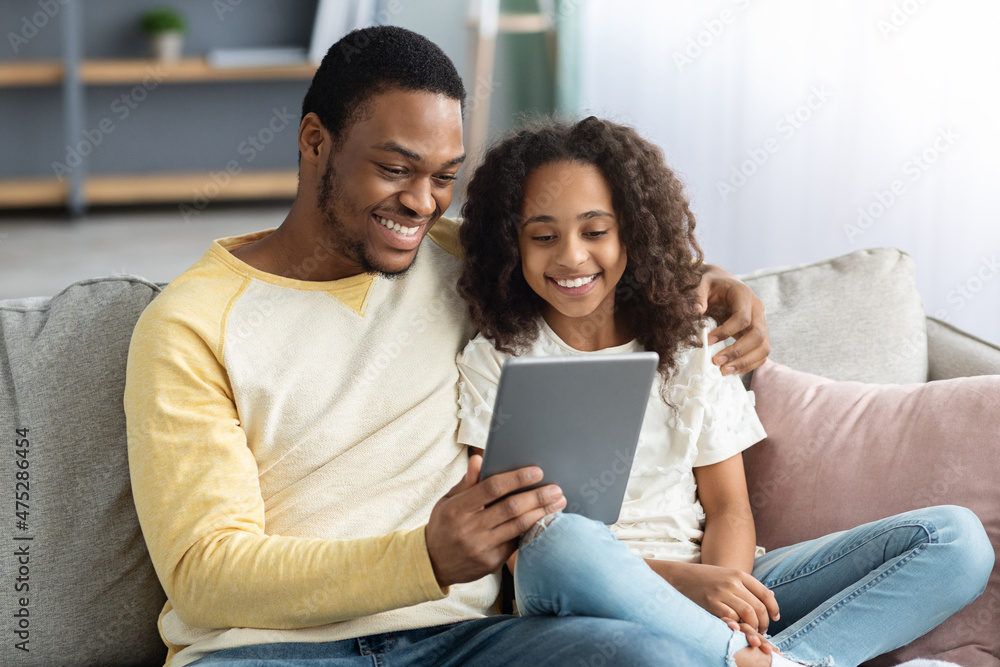 Fototapeta premium Happy black dad and daughter using digital tablet