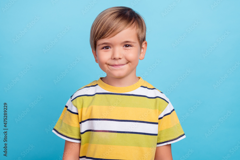 Portrait of attractive cheerful boy wearing striped tshirt isolated over vibrant blue color background Portrait of attractive cheerful boy wearing striped tshirt isolated over vibrant blue color background