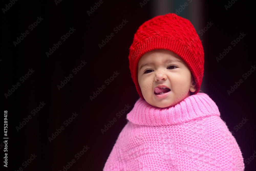 13 months old Indian baby dressed in red winter cap and pink pohcho giving cute expressions while taking her tounge out. 13 months old Indian baby dressed in red winter cap and pink pohcho giving cute expressions while taking her tounge out.