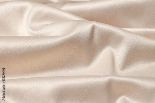 Silk atlas soft tender beige color fabric with shiny romantic curves macro