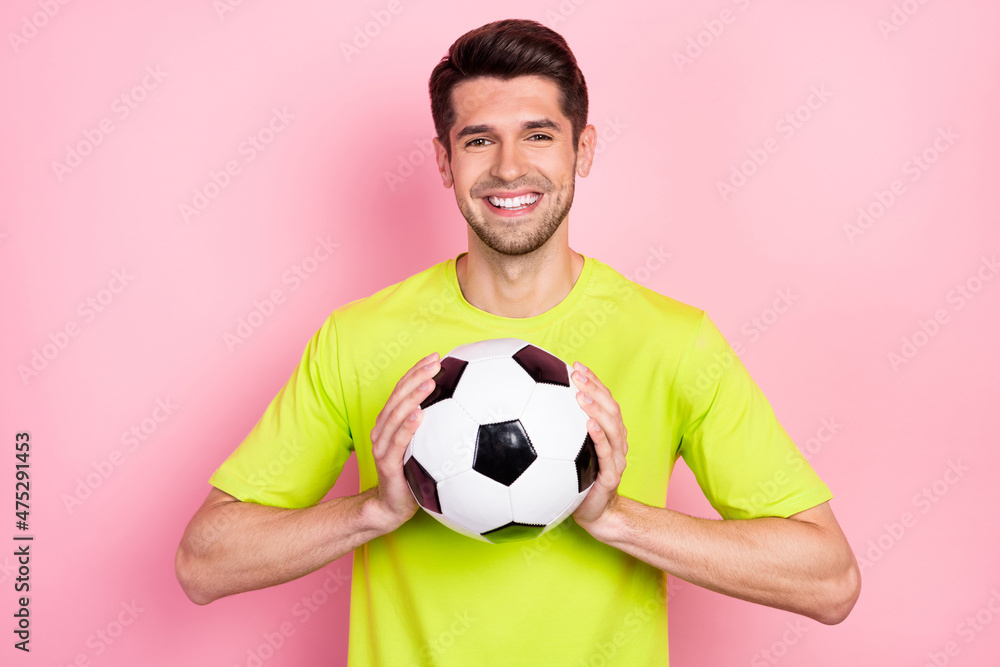 Portrait of attractive cheerful guy holding in hands soccer ball isolated over pink pastel color background Portrait of attractive cheerful guy holding in hands soccer ball isolated over pink pastel color background