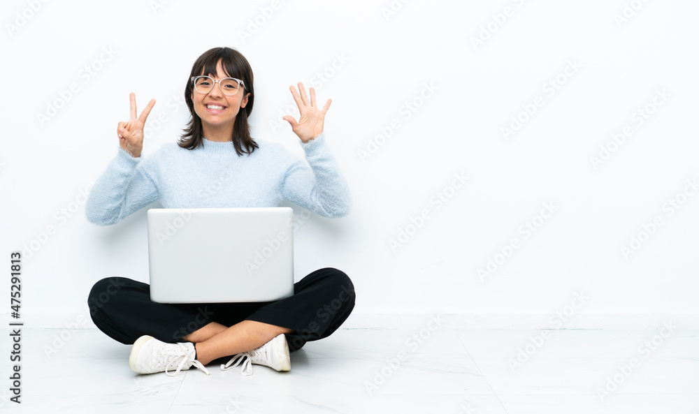 Young mixed race woman sitting on the floor with laptop isolated on white background counting seven with fingers Young mixed race woman sitting on the floor with laptop isolated on white background counting seven with fingers