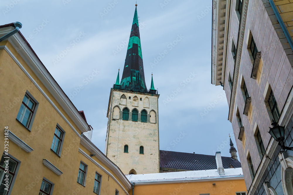 Obraz premium Low-angle view of apartment buildings and the tower of the Saint Olaf's Church in overcast winter day, Tallinn Old Town, Estonia 