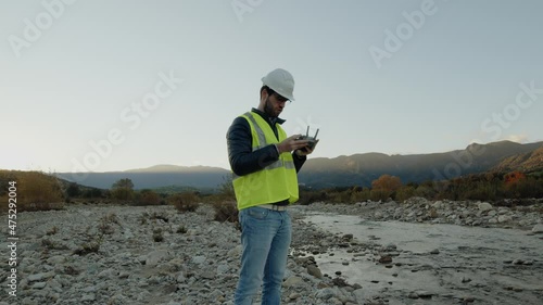 Ingegnere sta controllando il fiume con il drone per un sopralluogo photo