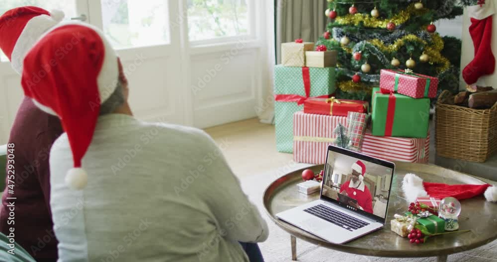 Diverse senior female friends using laptop for christmas video call with santa on screen Diverse senior female friends using laptop for christmas video call with santa on screen